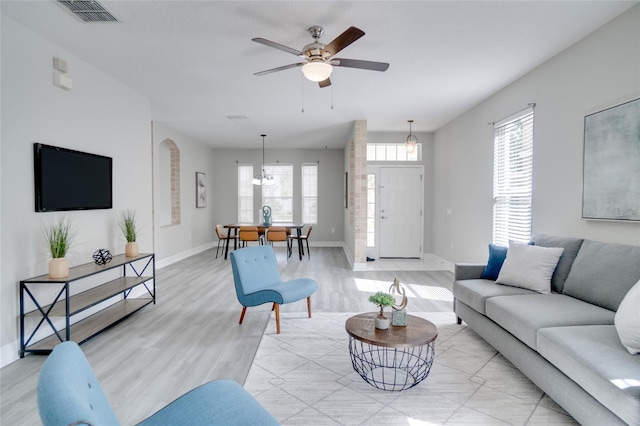 living room featuring visible vents, a ceiling fan, baseboards, and light wood-type flooring