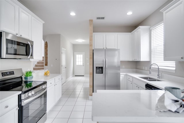 kitchen with a sink, light countertops, stainless steel appliances, white cabinetry, and visible vents