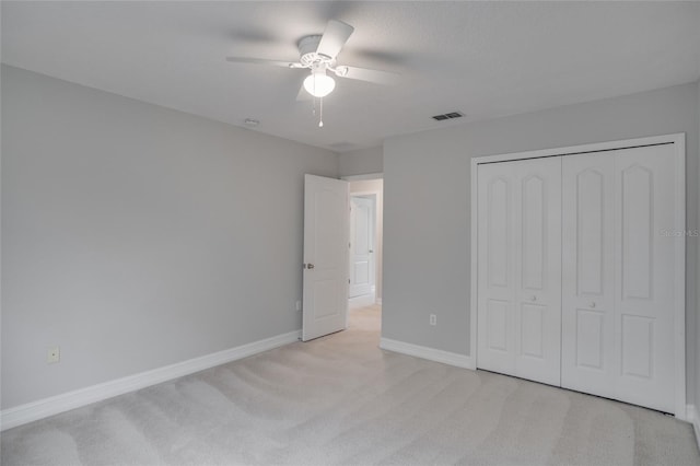 unfurnished bedroom featuring visible vents, a closet, light carpet, baseboards, and a ceiling fan