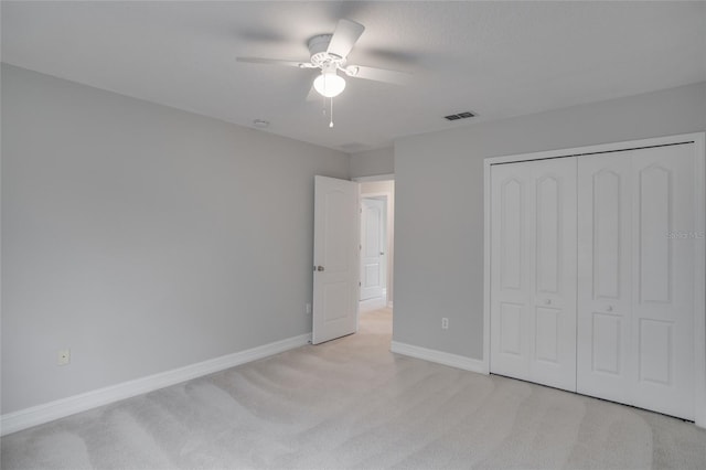 unfurnished bedroom with ceiling fan, light colored carpet, baseboards, visible vents, and a closet