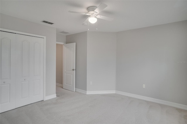 unfurnished bedroom featuring a ceiling fan, light colored carpet, visible vents, baseboards, and a closet