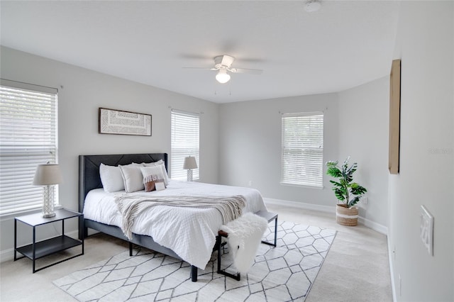 bedroom featuring baseboards, light colored carpet, and multiple windows
