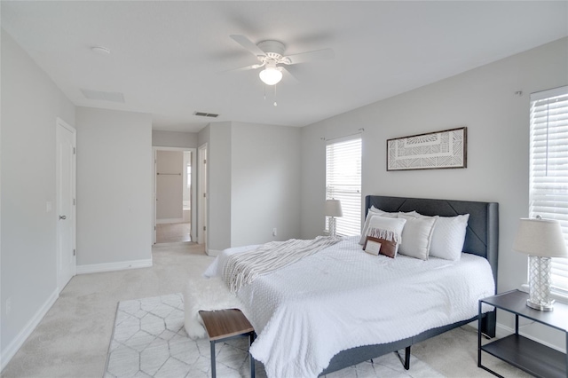 bedroom featuring visible vents, light carpet, baseboards, ceiling fan, and ensuite bath