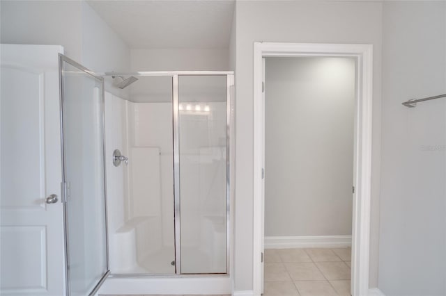 bathroom with tile patterned flooring, baseboards, and a shower stall