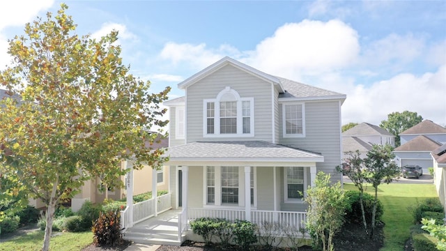 view of property featuring covered porch, a front lawn, and a garage