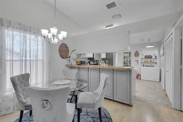 dining area with light hardwood / wood-style flooring, a healthy amount of sunlight, a notable chandelier, and washer / dryer