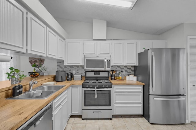 kitchen with white cabinetry, sink, stainless steel appliances, backsplash, and vaulted ceiling