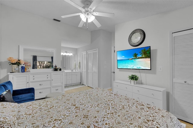 bedroom featuring connected bathroom, multiple closets, ceiling fan, sink, and a textured ceiling