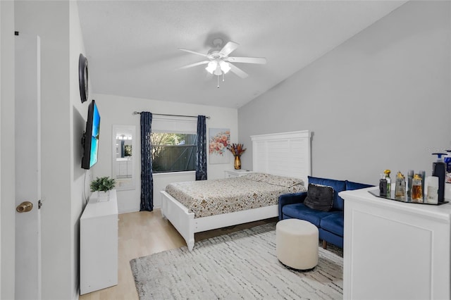 bedroom with ceiling fan, vaulted ceiling, and light wood-type flooring