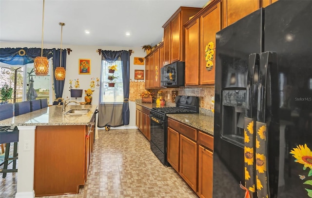 kitchen featuring black appliances, sink, pendant lighting, a breakfast bar area, and a center island with sink