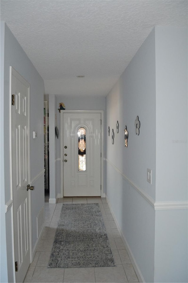 doorway featuring a textured ceiling and light tile patterned floors