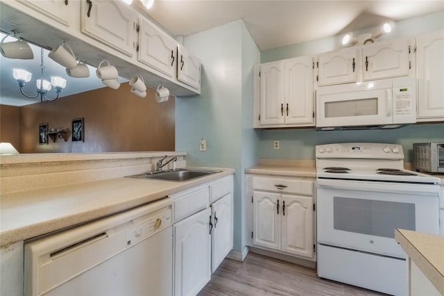 kitchen featuring white appliances, sink, white cabinetry, light hardwood / wood-style floors, and a chandelier