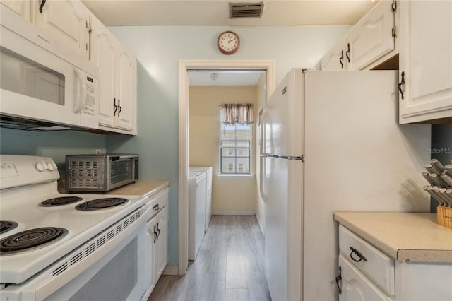 kitchen featuring white cabinets, washing machine and dryer, white appliances, and light hardwood / wood-style floors