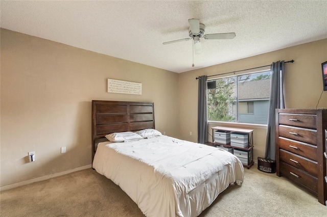 bedroom with a textured ceiling, light colored carpet, and ceiling fan