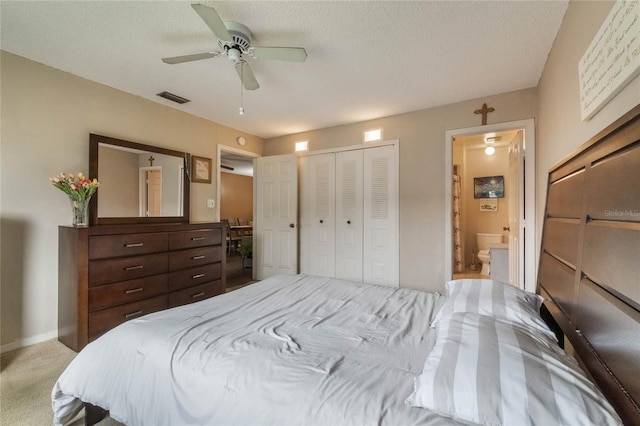 bedroom featuring ceiling fan, a textured ceiling, connected bathroom, a closet, and light colored carpet