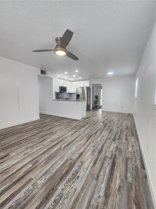 unfurnished living room featuring a textured ceiling, wood-type flooring, and ceiling fan