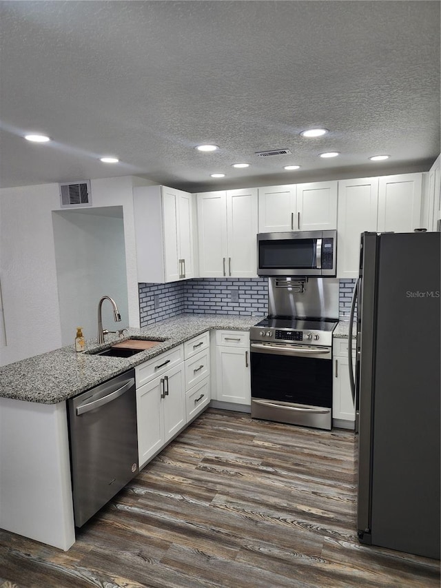 kitchen featuring white cabinetry, light stone countertops, dark wood-type flooring, sink, and stainless steel appliances