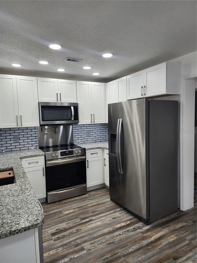 kitchen featuring white cabinetry, light stone countertops, appliances with stainless steel finishes, and dark hardwood / wood-style floors