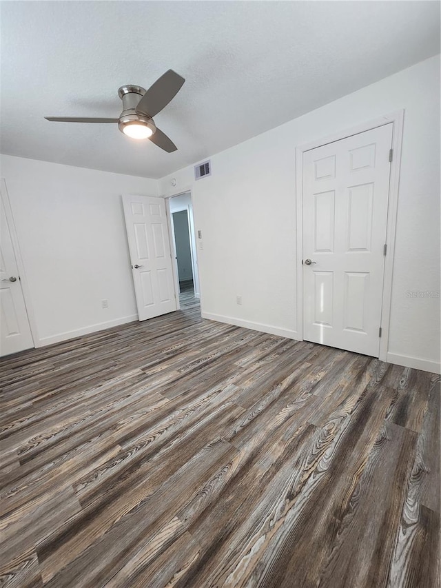 empty room featuring dark wood-type flooring and ceiling fan