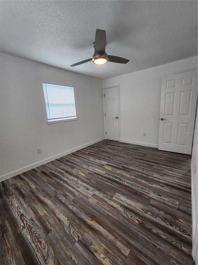 empty room featuring a textured ceiling, dark hardwood / wood-style floors, and ceiling fan