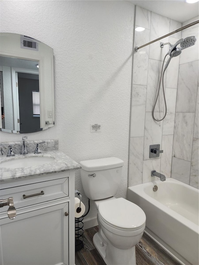 full bathroom featuring toilet, tiled shower / bath combo, vanity, and wood-type flooring