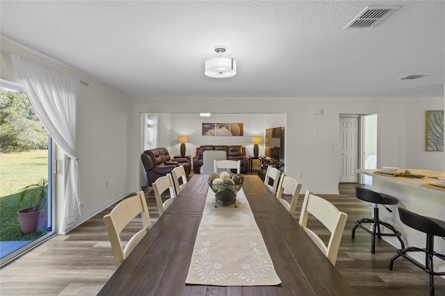 dining space with hardwood / wood-style floors and a textured ceiling