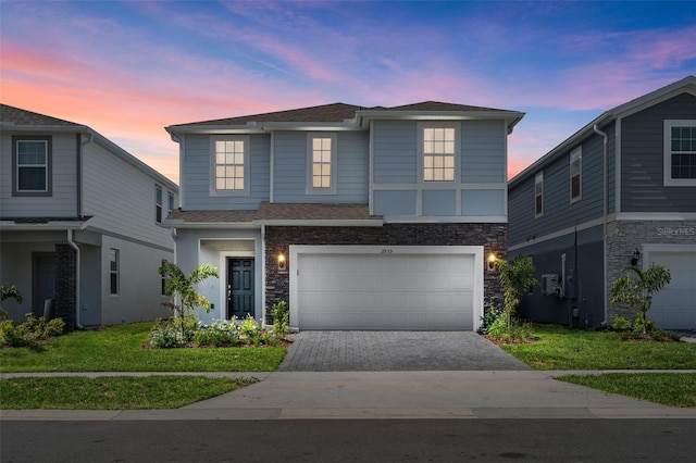 view of front of home featuring a garage, stone siding, a front lawn, and decorative driveway