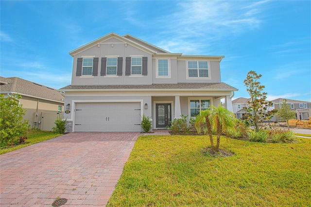 traditional home with a garage, decorative driveway, stucco siding, and a front yard