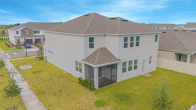 back of house with a sunroom, a garage, and a lawn