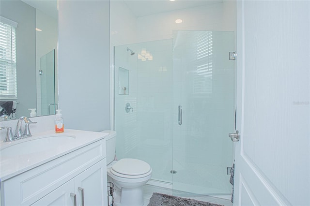 bathroom featuring vanity, a shower with shower door, and toilet