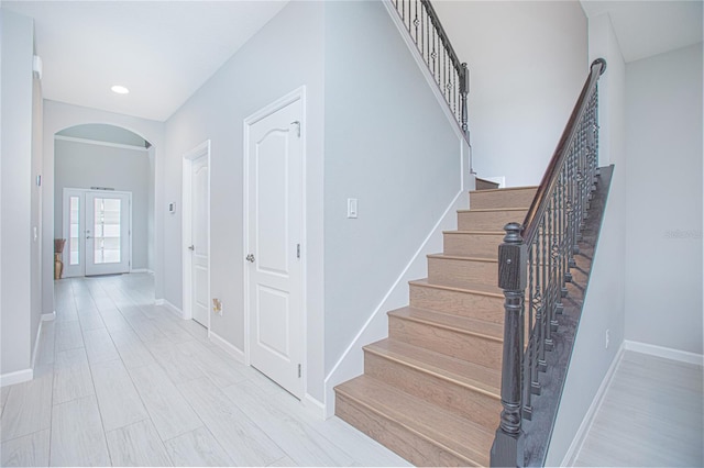 stairway with french doors and wood-type flooring