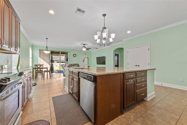 kitchen featuring sink, appliances with stainless steel finishes, decorative light fixtures, and a center island with sink