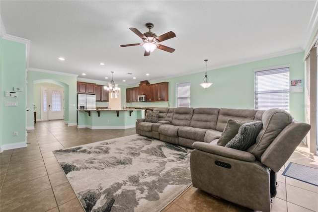 tiled living room with ornamental molding and ceiling fan with notable chandelier