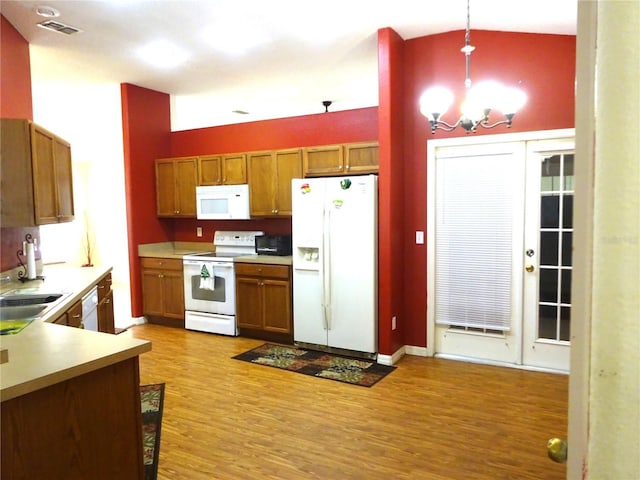 721 Willow Run St, Minneola, FL 34715 - kitchen with white appliances, a chandelier, light wood-style flooring, brown cabinets, and light countertops