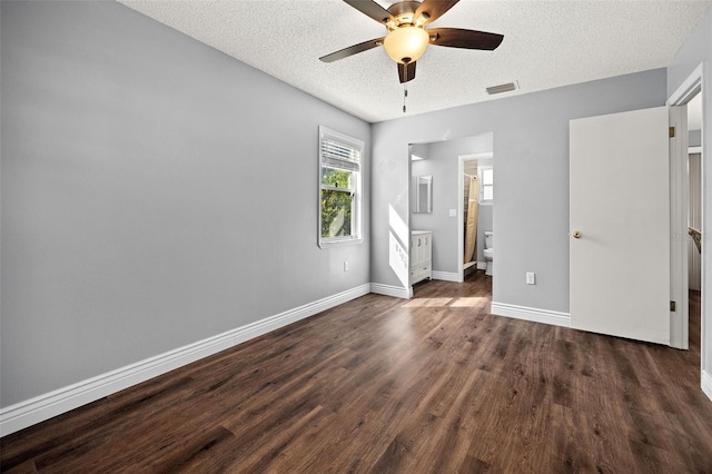 unfurnished bedroom featuring connected bathroom, dark wood-type flooring, a textured ceiling, and ceiling fan