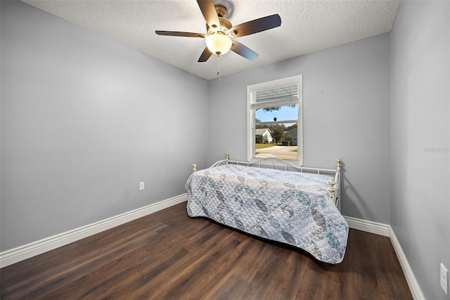 bedroom with a textured ceiling, dark hardwood / wood-style floors, and ceiling fan