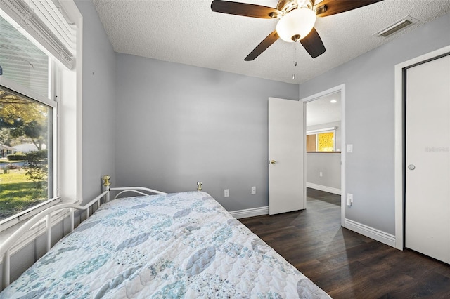 bedroom with a textured ceiling, dark wood-type flooring, and ceiling fan