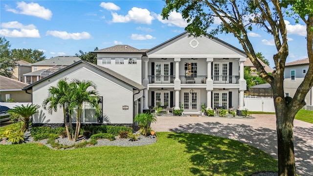 view of front of house with ceiling fan, french doors, a balcony, and a front yard