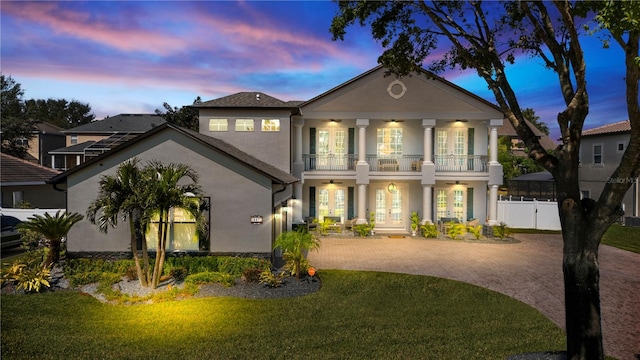 view of front of property with a lawn, ceiling fan, a balcony, and french doors