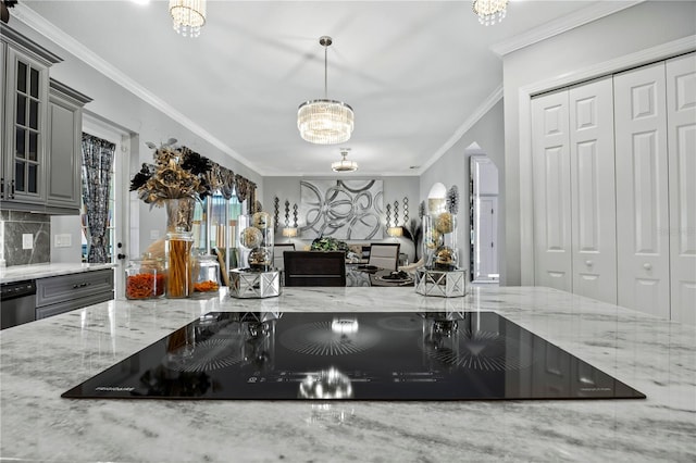 kitchen featuring gray cabinetry, black electric stovetop, crown molding, decorative light fixtures, and light stone counters