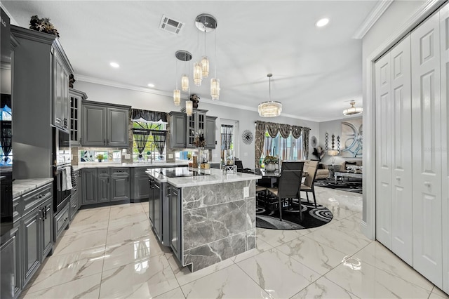 kitchen with decorative light fixtures, a center island, gray cabinets, and ornamental molding