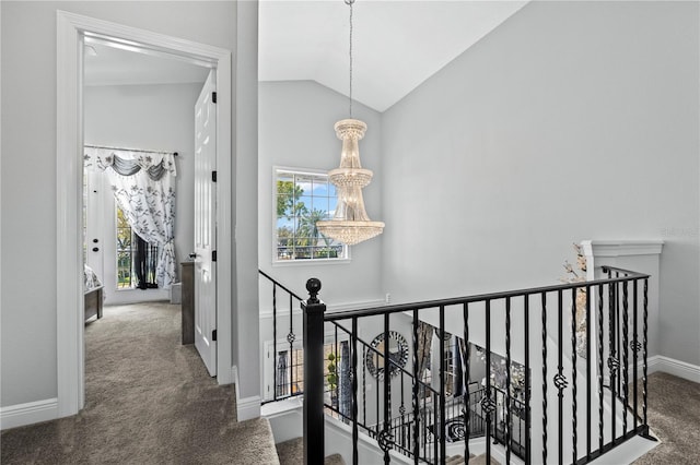 hall featuring a chandelier, dark colored carpet, and lofted ceiling