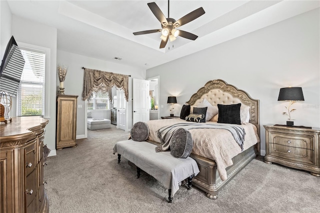 carpeted bedroom featuring a tray ceiling and ceiling fan