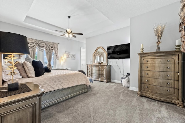 carpeted bedroom featuring ceiling fan, a textured ceiling, and a tray ceiling