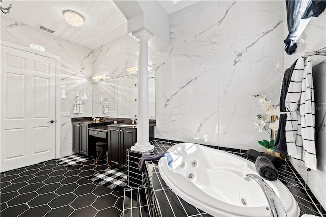 bathroom featuring tile patterned floors, ornate columns, vanity, tile walls, and tiled bath