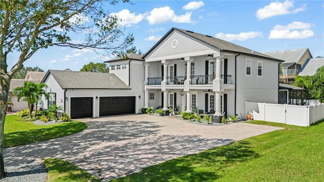 greek revival house with a balcony, a front yard, and a garage