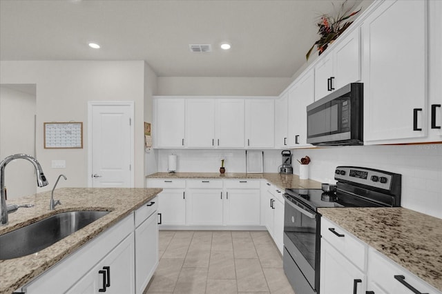 kitchen with white cabinetry, stainless steel appliances, sink, and light stone counters