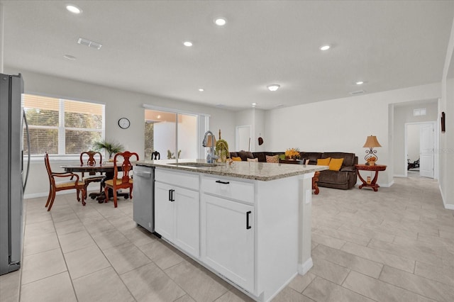 kitchen with an island with sink, stainless steel appliances, sink, white cabinets, and light stone counters