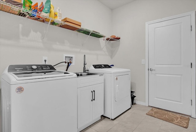 laundry area with washer and dryer, cabinets, and light tile patterned floors