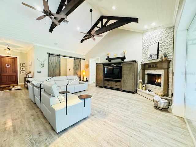 living room with a fireplace, a barn door, high vaulted ceiling, ornamental molding, and light hardwood / wood-style flooring